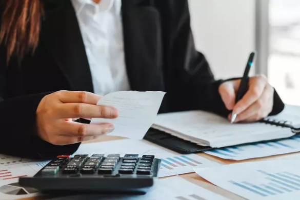 Concurseira realizando anotações e ponderando as principais diferenças entre os cargos de Analista Tributário e Auditor Fiscal.